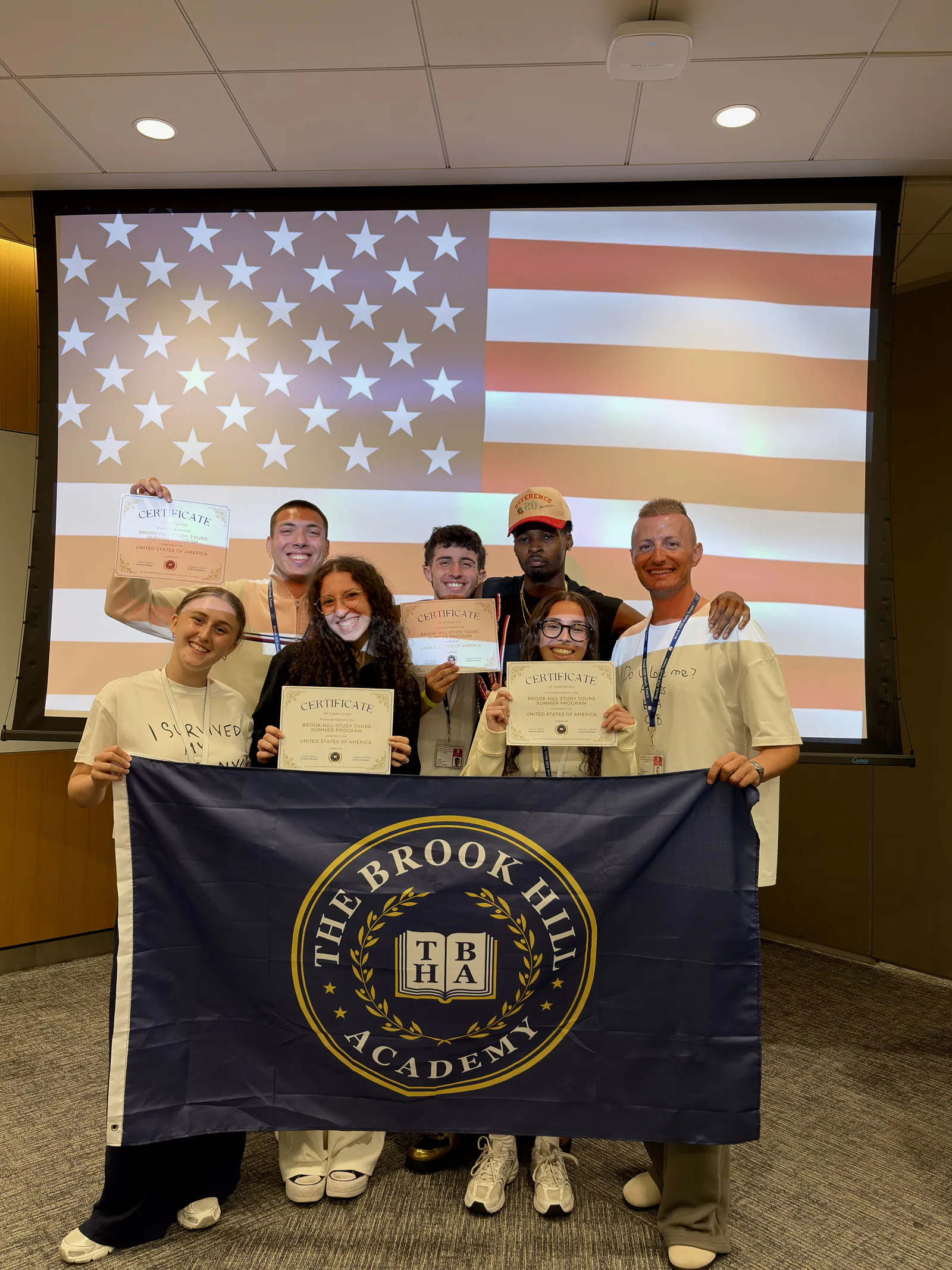 Students celebrating with their certificates and a Brook Hill flag