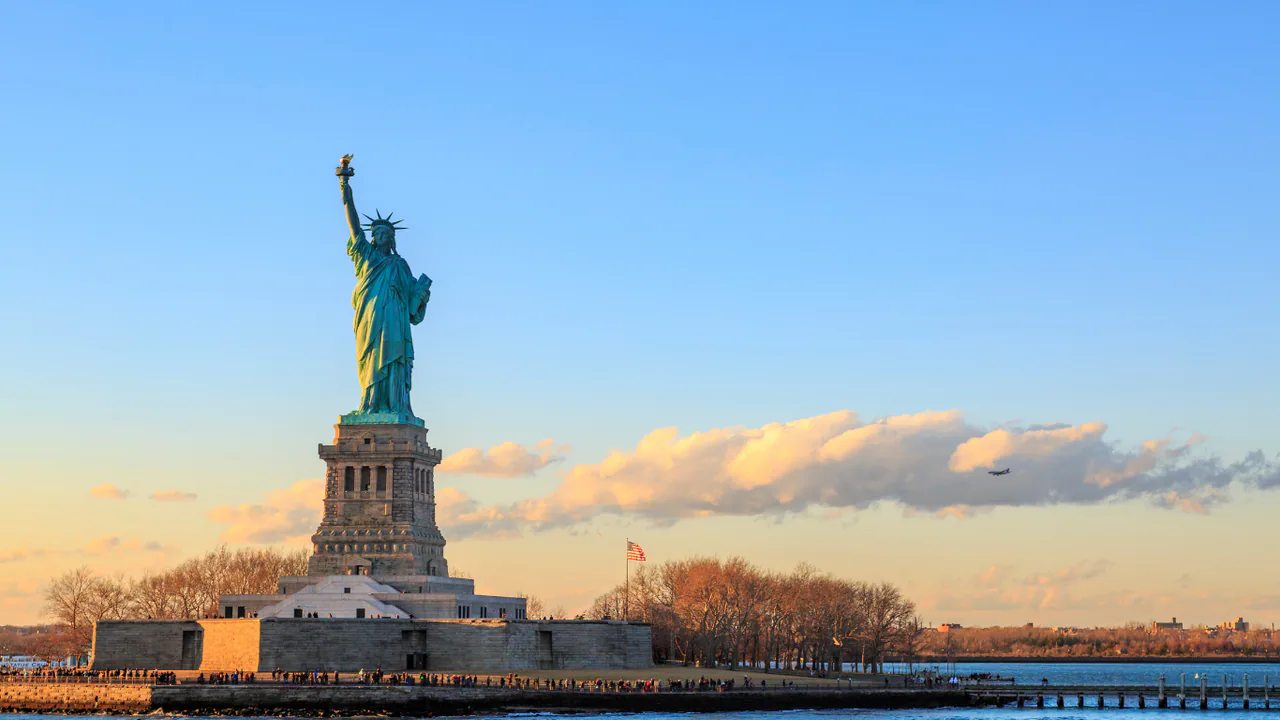 The Statue of Liberty beside New York Harbor at sunset